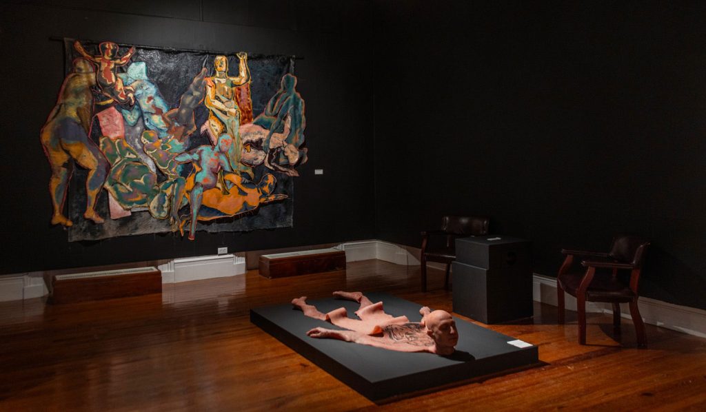 Edrin Symonette’s Man Skin Rug (2025), mounted on the floor, and KENECHI’S The Muses: Currency (2025) exhibited at NELEVEN: Into the Void. Photo courtesy the National Art Gallery of The Bahamas